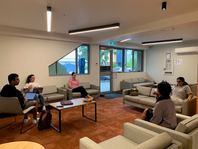 Students sitting in the new common room at the Department of Rural Health, featuring lounge chairs and small coffee tables.
