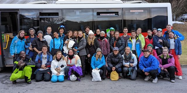 Medical students who participated in the Alpine Showcase stand in front of a bus for a group photo at the base of Falls Creek.