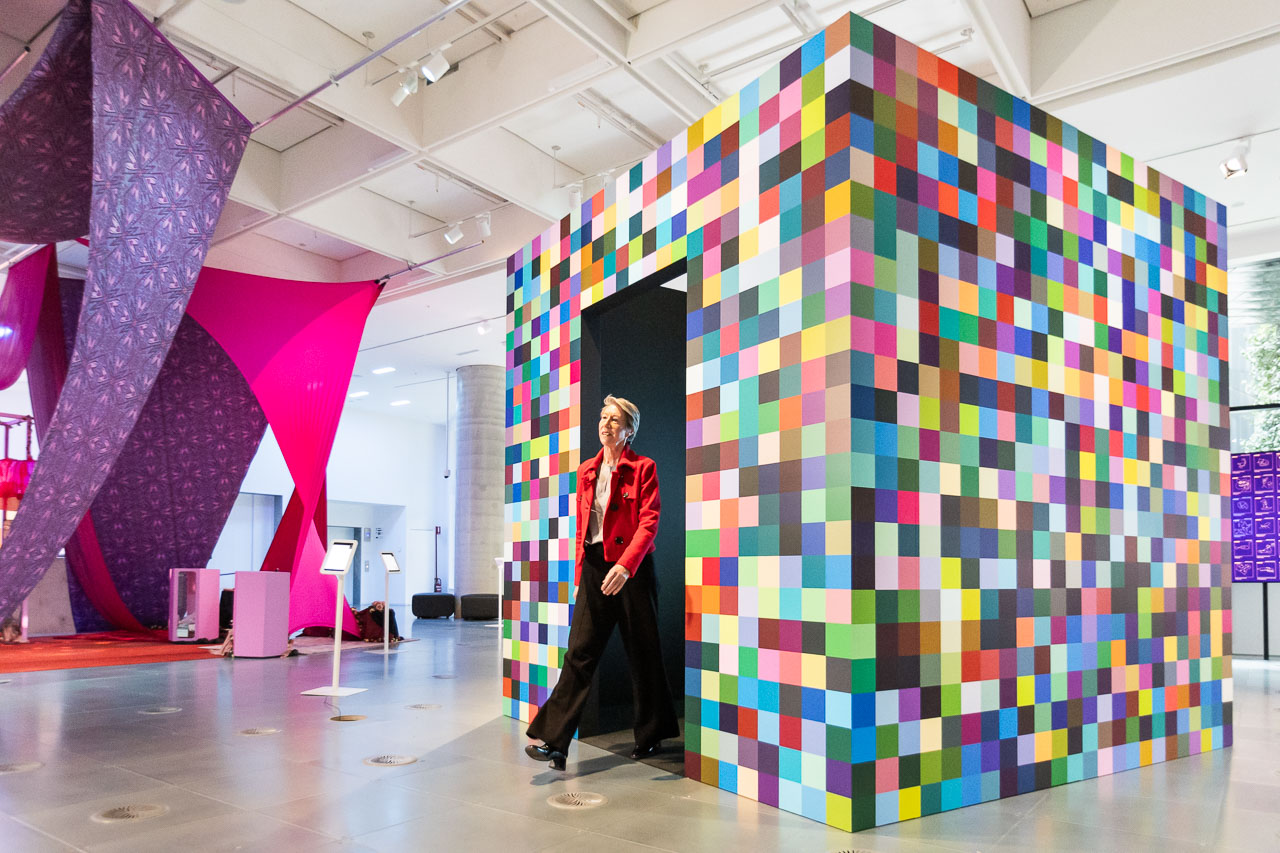 Professor Susan Sawyer AM walks out of a colourful cube from installation “512-BIT” at the Science Gallery Melbourne