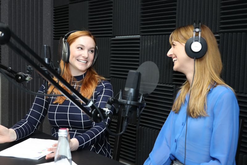 Dr Anneliese Willems and Dr Sarah Adamson in the studio. In front of them are microphones and in the background are textured soundproofing walls.