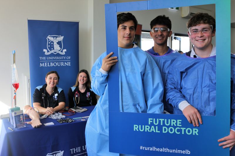 Rural medical students pose together with a cardboard frame which reads 'Future Rural Doctor, #ruralhealthunimelb'.