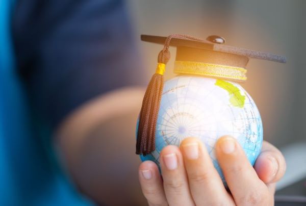 Join the Paediatric Academy. Image of a persons hand holding a small globe with a graduation cap on top of it. 