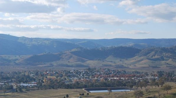 Tallangatta is a Victorian rural township located 338 km north of Melbourne. Image of the green hills of the town from a distance, with a lake near the front. 