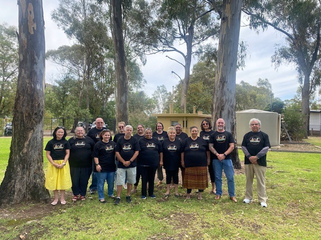 Study participants standing outside in a grassy park with scattered large gum trees. About 15 participants are pictured.