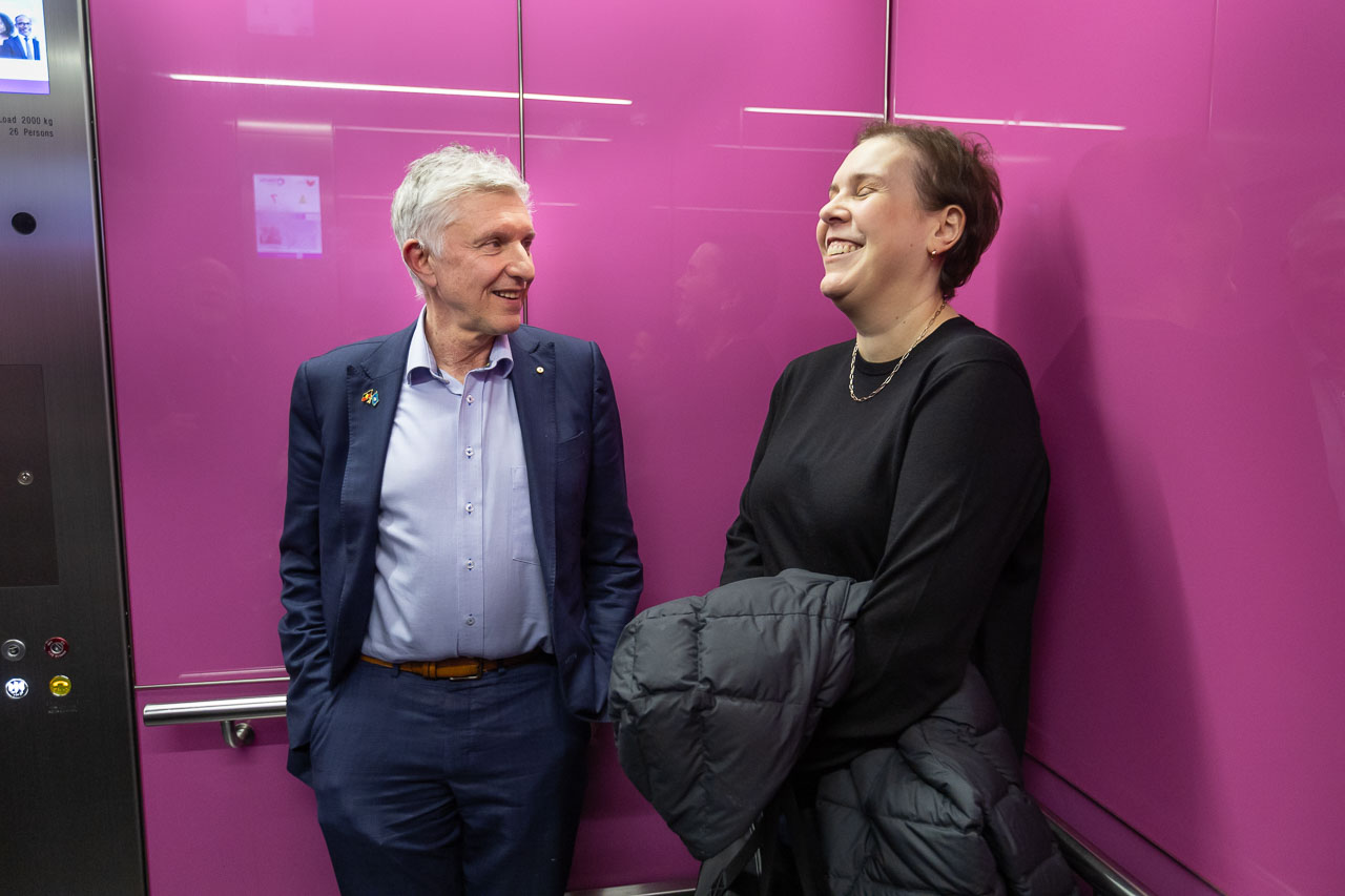 Alum Professor Grant McArthur, left, and patient and long-time friend Melissa Sheldon, right, smile at each other while having a casual conversation inside a pink elevator at the VCCC