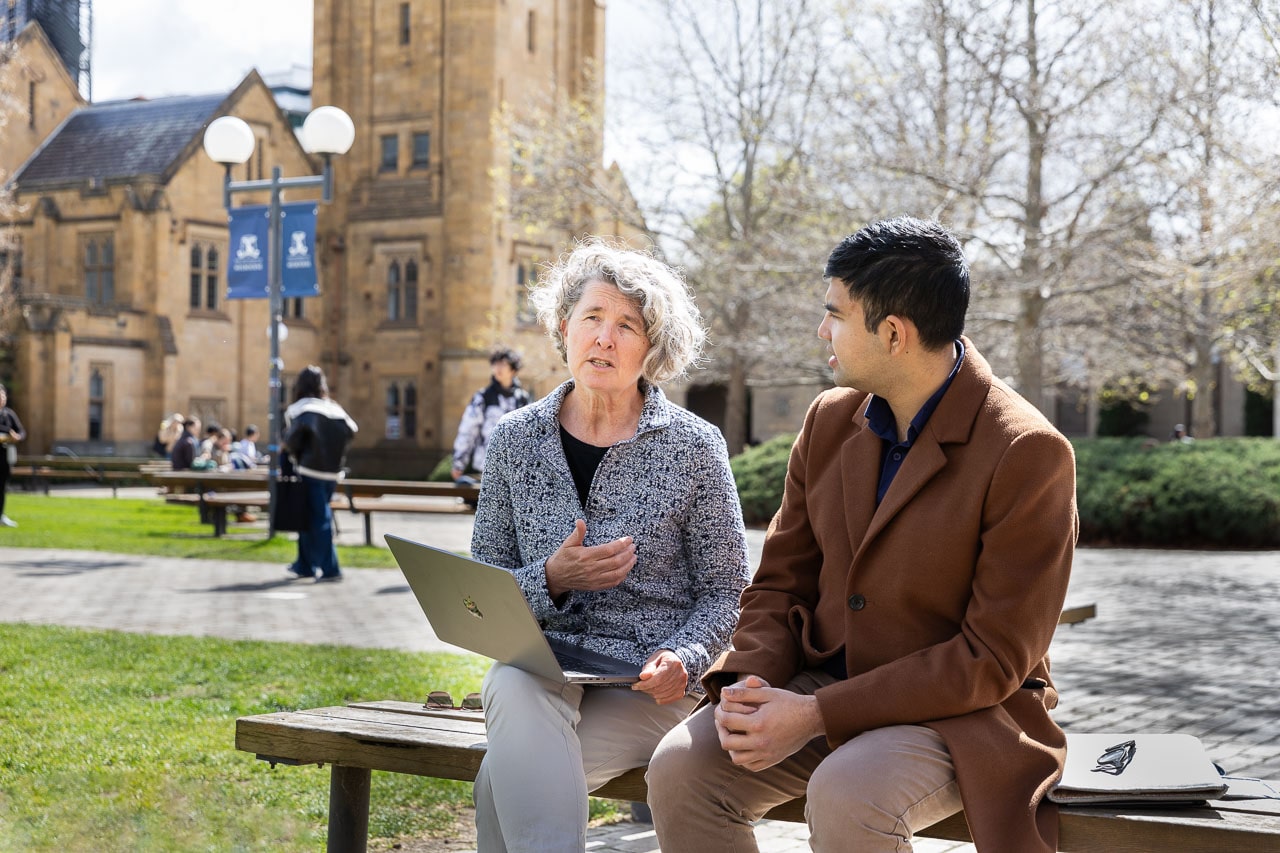 Alum Associate Professor Lisa Cheshire, left, and MD and Master of Biomedical Engineering student Farhan Islam, right, talk to each other while sitting on a bench in the middle of the Parkville campus