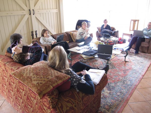 Photo of 7 researchers working together, they are sitting in armchairs and a sofa